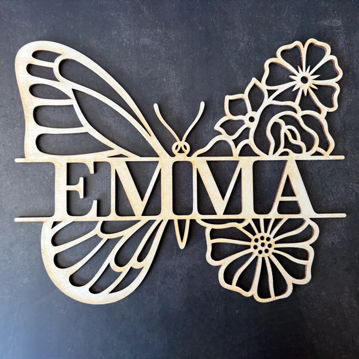 Prénom Emma découpé sur mesure en bois naturel clair intégré dans un motif ajouré d'aile de papillon et de fleurs